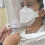 Close-up of a person adjusting a protective mask for a perfect fit